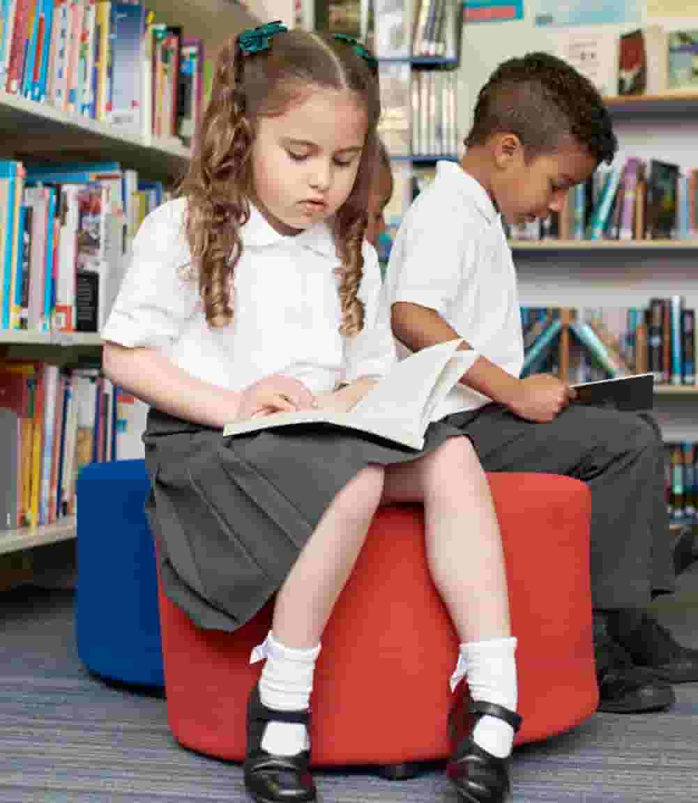 Two children sitting on a bench in the library
