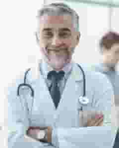 A man in a doctor 's uniform is smiling.