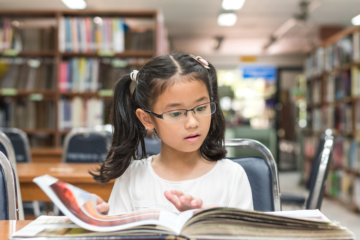 A girl with glasses is reading a book