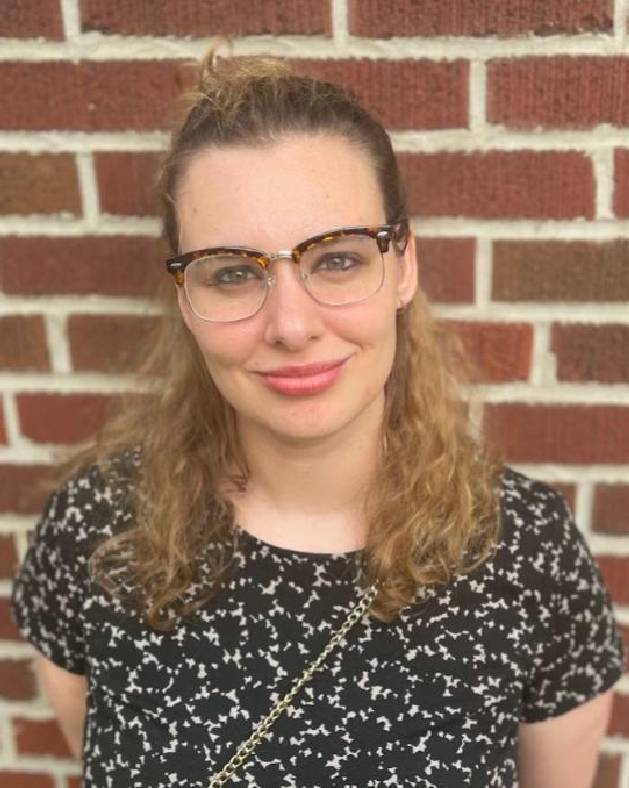 Woman smiling in front of a brick wall.